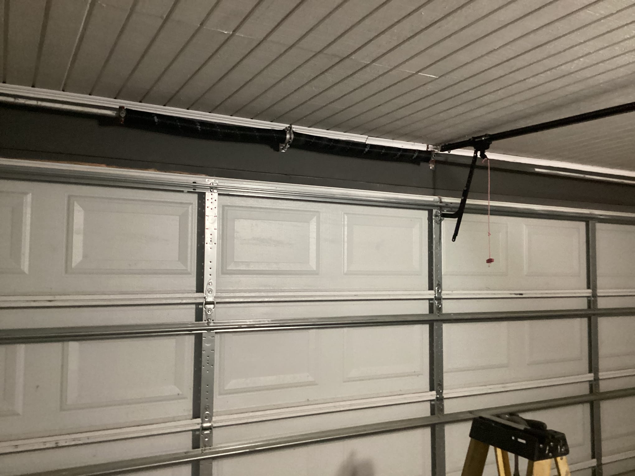 New torsion spring and lifting hardware installed above a garage door