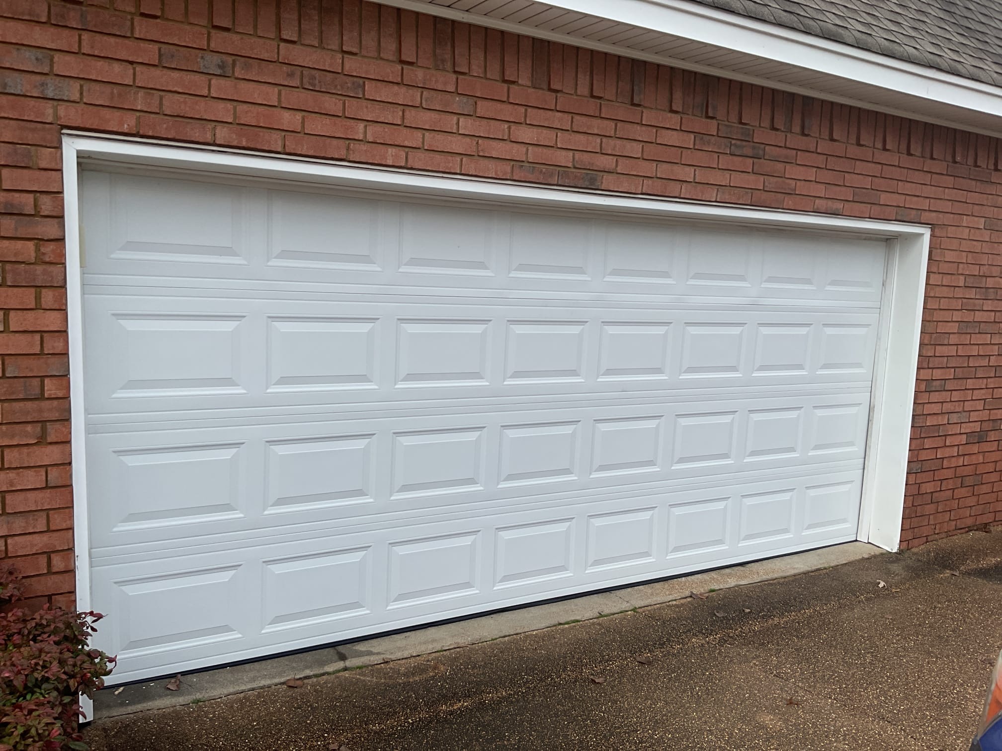 Finished white raised-panel garage door installed on a brick home in Greater Memphis